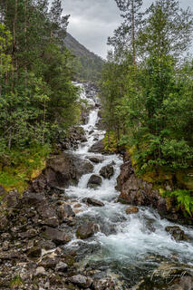 View from the bottom of the hiking trail at Langfoss Waterfall in Haugesund, Norway, captured on a rainy day before a strenuous uphill trek.
