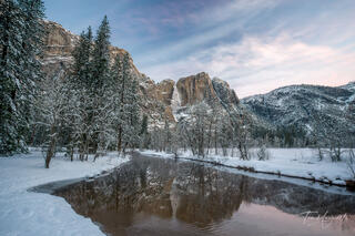Winter sunrise photograph of Yosemite Falls reflected in the Merced River from Swinging Bridge in Yosemite National Park.