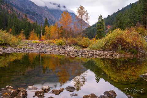 Fine art landscape photograph of Tumwater Canyon in Washington, showing golden autumn trees, calm reflections on the Wenatchee River, and misty mountains.