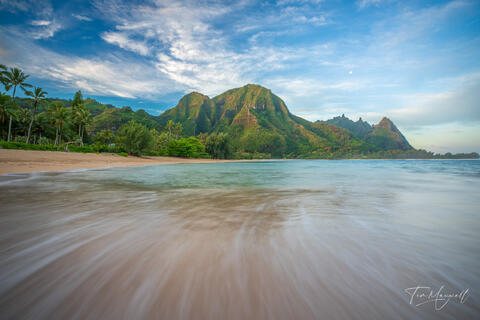 Fine-art photograph of Makana Mountain at sunrise from Tunnels Beach on Kauai’s North Shore, with soft waves leading toward the green cliffs.