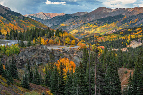 Fine art photograph of the Million Dollar Highway near Ouray, Colorado, with vibrant autumn aspens and winding mountain road beneath dramatic peaks.